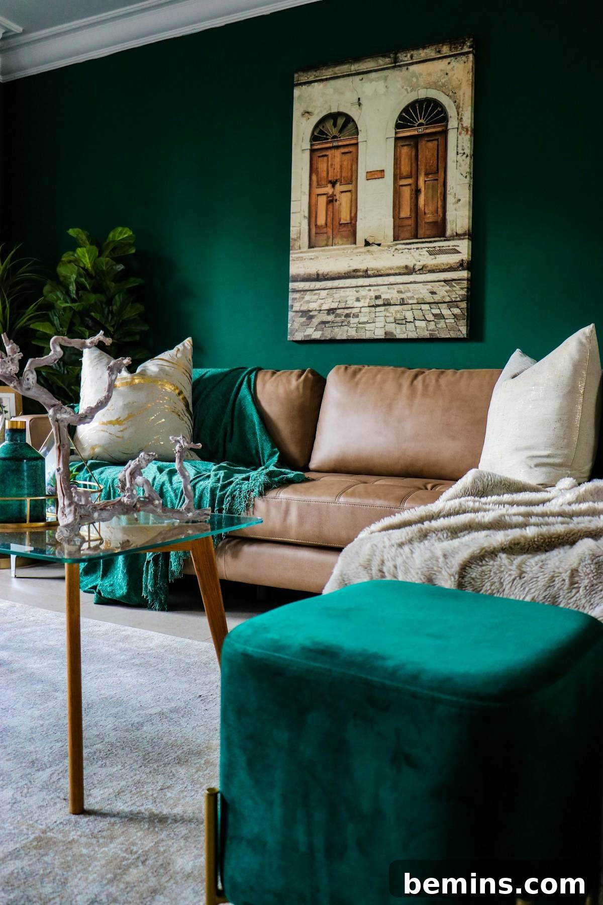 beige leather couch and green ottoman in dark emerald green painted walls