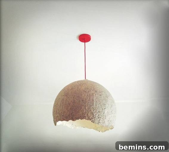 A modern paper mache pendant lamp hanging in a stylish room