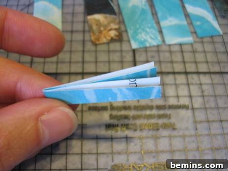 Close-up of folding a paper strip in half to establish the center point for subsequent folds.