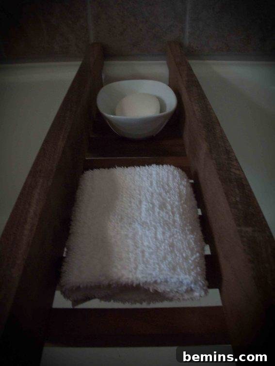 Finished wooden bathtub caddy sitting across a white bathtub.