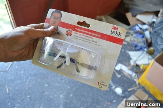 A person is holding a pair of 3M goggles in the package.