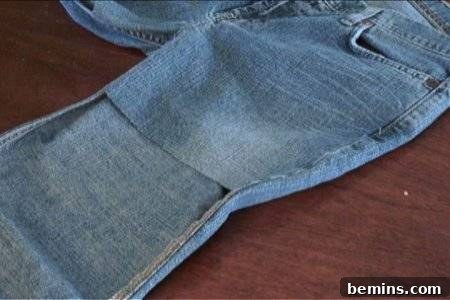 How to Sew Your Own Overalls 17 A pair of blue jeans with the front part of the leg cut off in a square.