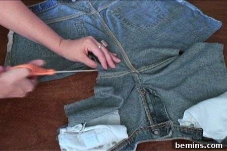 How to Sew Your Own Overalls 29 Hands using scissors to cut the crotch seam of a pair of denim bottoms turned inside-out.