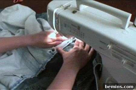 How to Sew Your Own Overalls 44 A person stitching a piece of cloth with a white sewing machine.