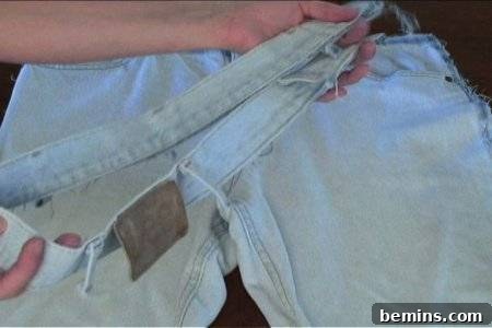 Woman cut the top belt of the jean pant.