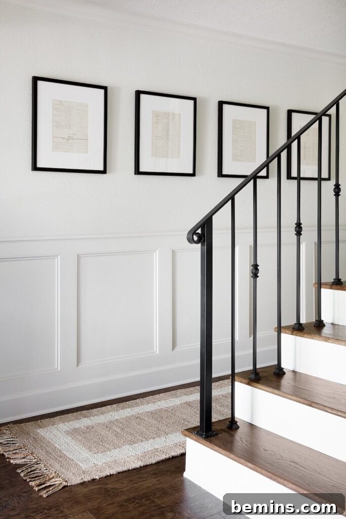 Charming Wainscoting: 21 Ways to Elevate Your Home 7 Modern Flat Panel Wainscoting against a white wall near stairs, wood flooring and black framed paintings.