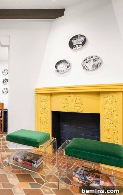 Yellow painted brick fireplace with black bricks inside and two green chairs