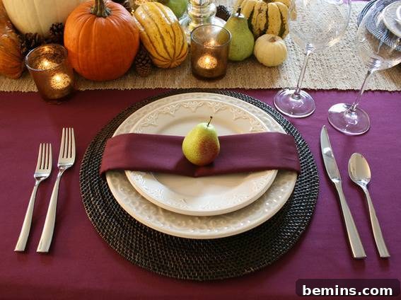 Thanksgiving table setting with deep jewel tones and fruit accents.