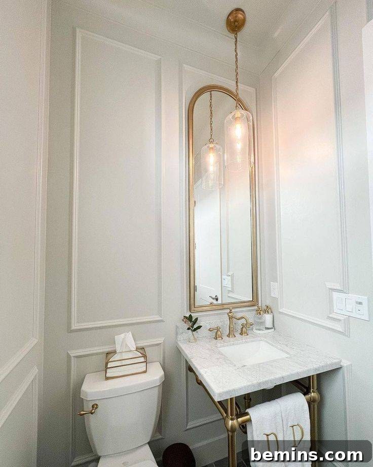 Cream walled bathroom with sink and toilet featuring large mirror on wainscoted wall 