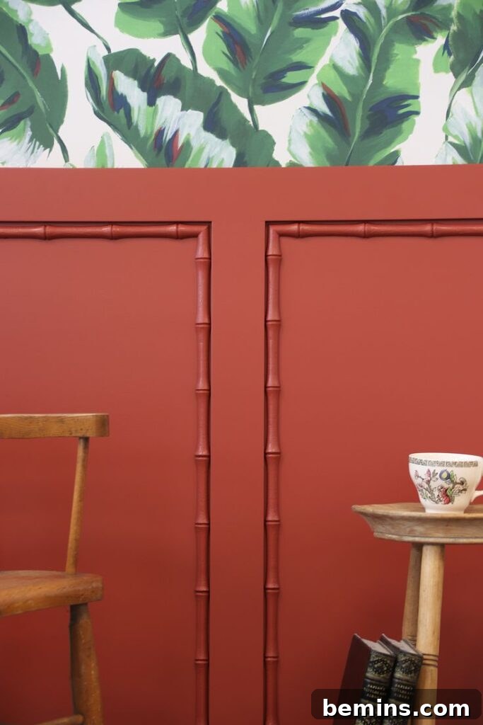 Red bamboo wainscoting on wall with green floral wallpaper