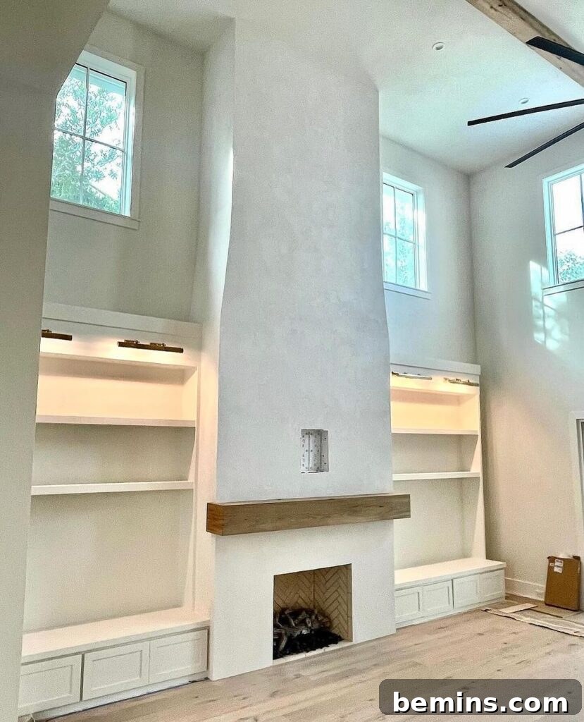 White stucco fireplace with brown wood mantle and simple decor in a modern living room