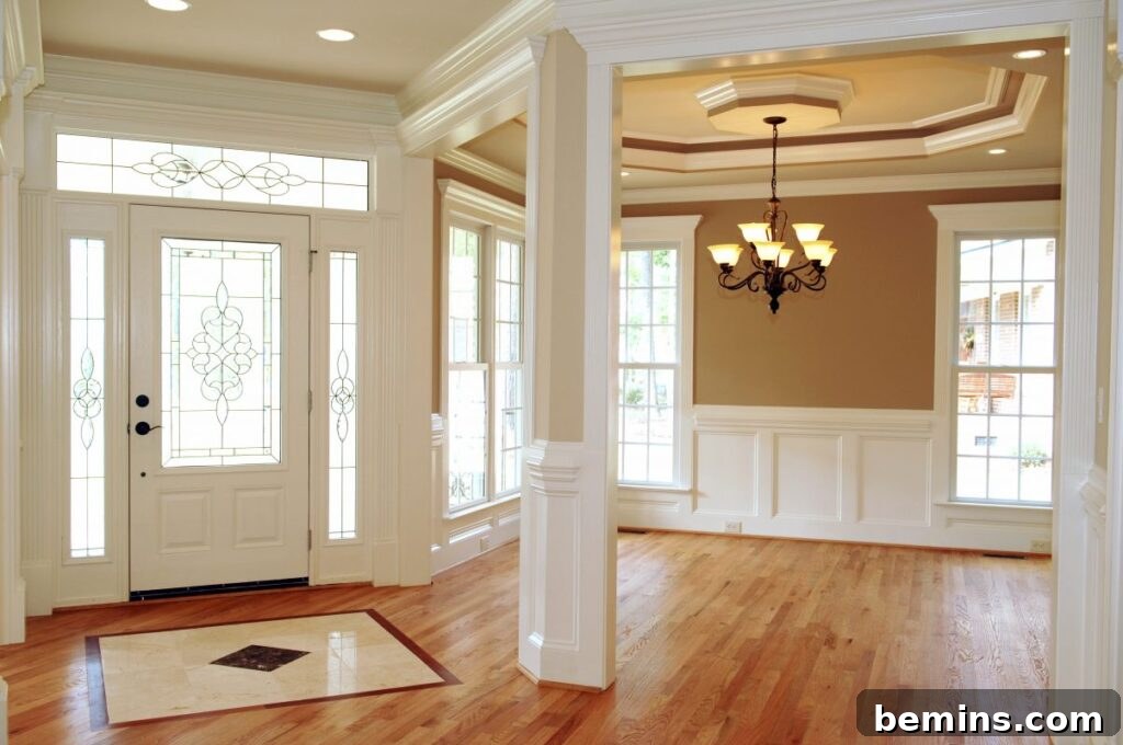 White living room with brown walls and wooden flooring, with white baseboard and crown molding wainscoting
