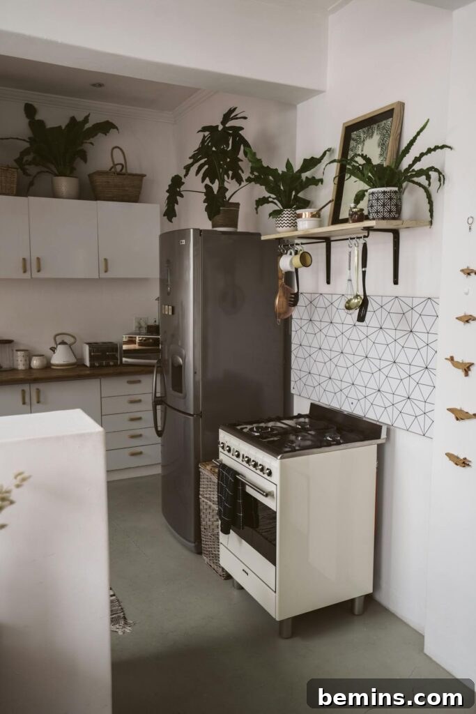 A stylish kitchen featuring a sleek refrigerator, stove, and greenery for a modern touch.