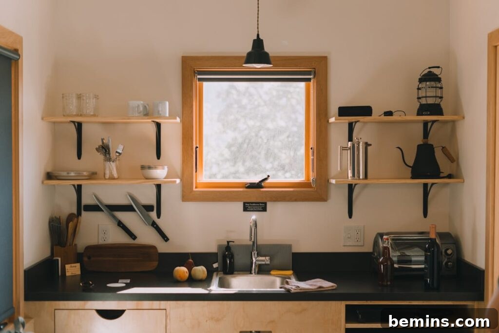 Modern kitchen interior with wooden shelves and a hanging lamp above the sink.