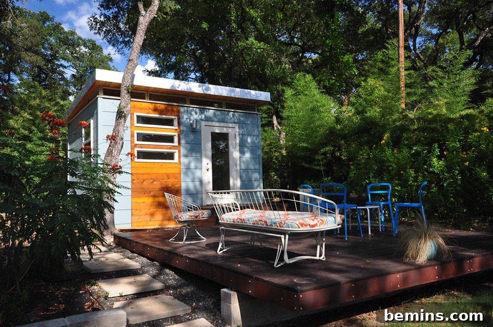 Blue shed with large brown wooden deck featuring cushioned seats