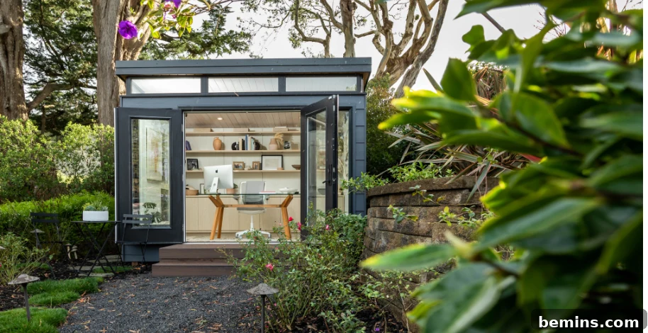 Grey shed in lush green backyard with office desk and computer inside