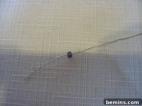 Steel wire placed into a black bead on fabric.