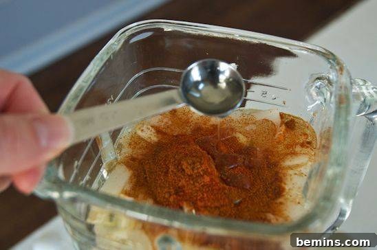 Adding liquid Castile soap to the blender with the other ingredients for the insecticide