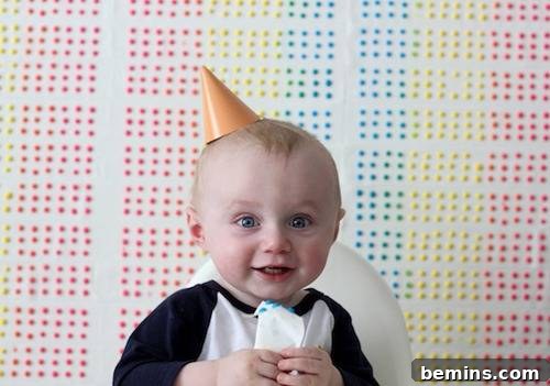 DIY Wall Decor: 10 Vibrant Art Projects to Personalize Your Space 3 A toddler with a birthday hat holding candy buttons, showcasing a fun photo booth backdrop idea.
