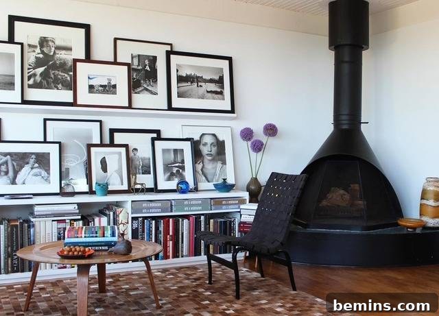 A wall featuring stacked family photos on a shelf, displayed next to a large black wood stove in a cozy living room.