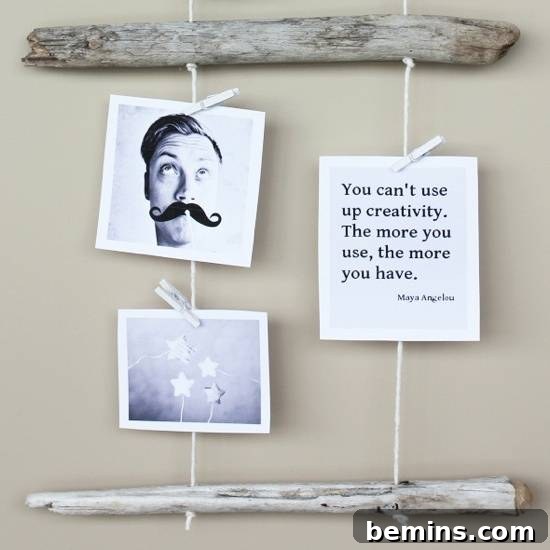 A rustic driftwood photo display featuring photos clipped to ropes strung between two logs.