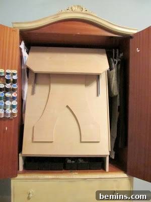 An open cupboard with a folded table inside. The interior of a DIY sewing cabinet.