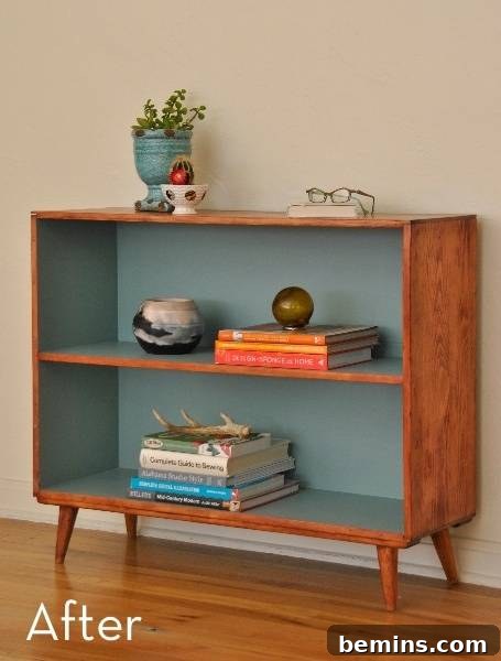 A wooden and blue shelf has books and decoration on it. The after image of a beautifully renovated mid-century bookshelf.
