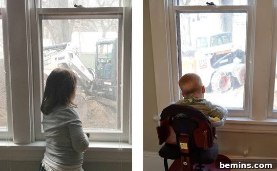 Children watching a small tractor from a window.