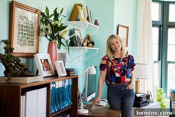 A woman standing in a well-organized office, surrounded by electronics, binders, and photos, showcasing a productive and inspiring workspace.