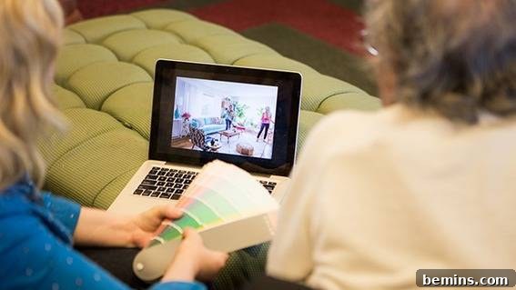 Two women reviewing design plans on a laptop, discussing paint color options and collaborating on the senior living makeover project.