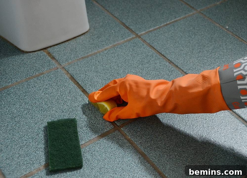 Close-up of lemon juice being applied to grout, demonstrating a natural mold removal solution.