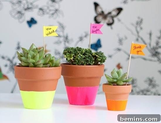 Three terra cotta flower pots with neon-dipped bottoms and matching plant markers.