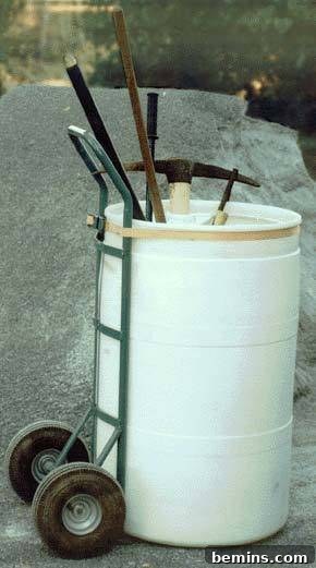 Garden tools sitting in a round white container that is strapped to a lift