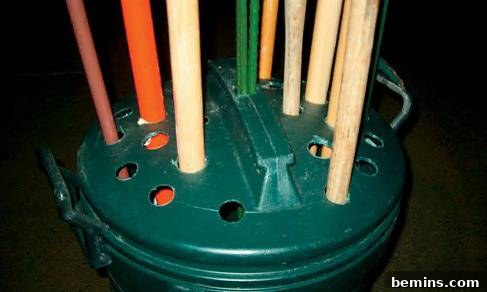 Holes cut into the lid of a garbage can to store brooms, mops, etc.