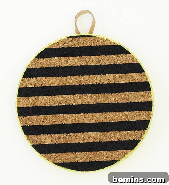 A corkboard has black horizontal stripes and a hanging loop.