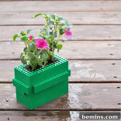 Purple flowers growing in a green Lego planter outdoors.