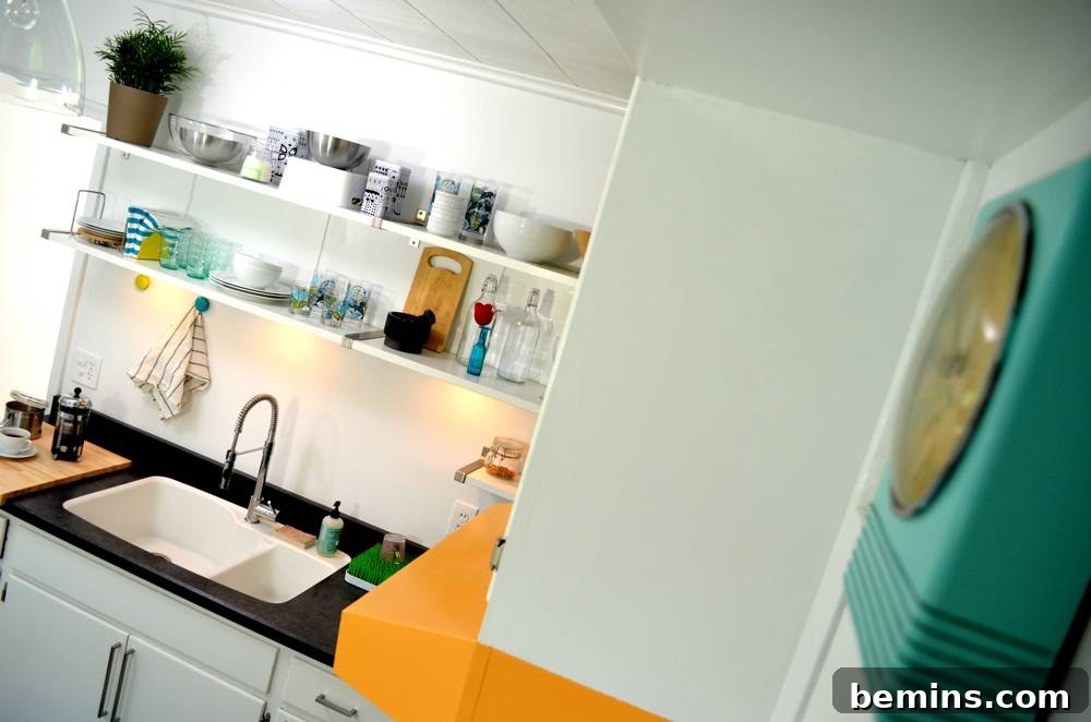 The kitchen sink with open shelves above it, and the teal clock on the wall.