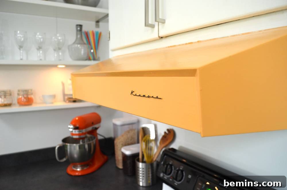 A kitchen with orange range hood, white shelves, and colorful accessories.