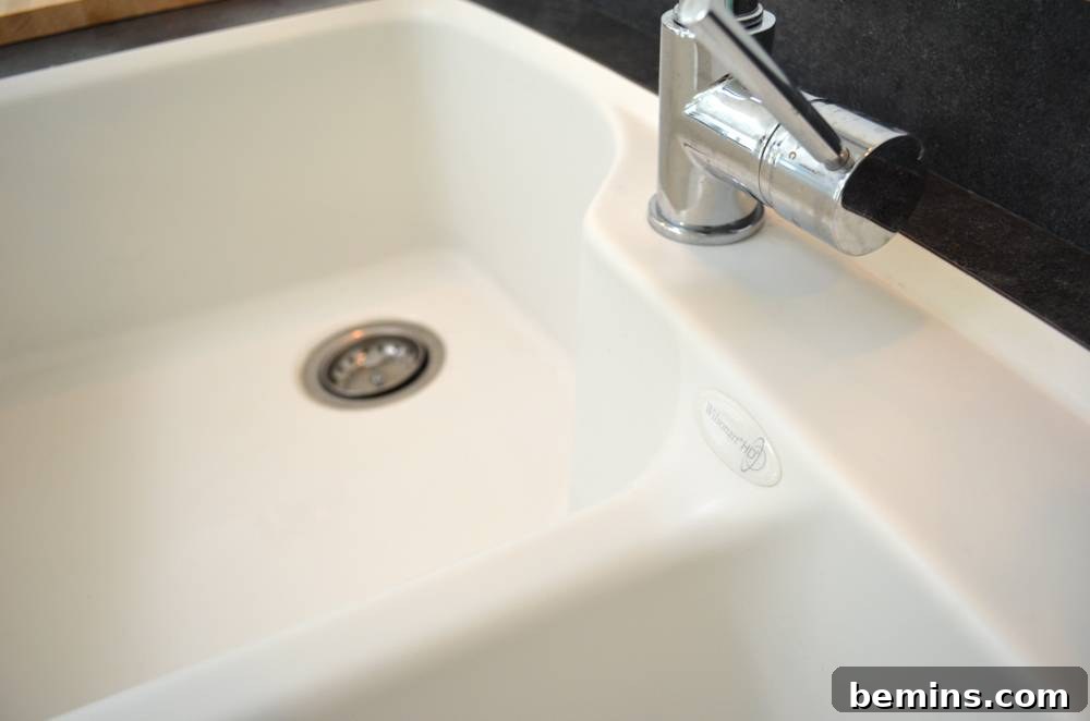 A double basin white sink set in a dark countertop.