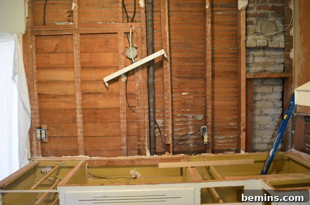 During: The wall with the upper cabinets removed, revealing the bare studs.