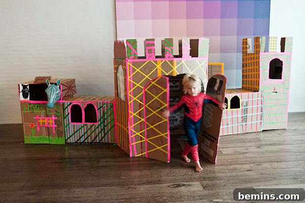 Cardboard Creations: 12 DIY Play Projects for Kids 13 A child dressed as Spiderman emerging from a beautifully crafted cardboard castle.
