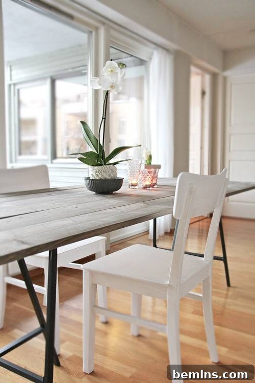 A minimalist dining area with a driftwood-stained table positioned in front of large windows.
