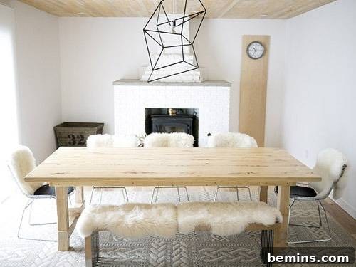 A light-colored farmhouse table with removable extensions, surrounded by chairs and a bench in a bright white room.