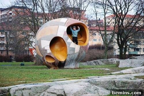 Playgrounds Reimagined: 5 Modern Wonders for Kids 3 A person in a blue shirt is standing inside of a piece of art in a park.