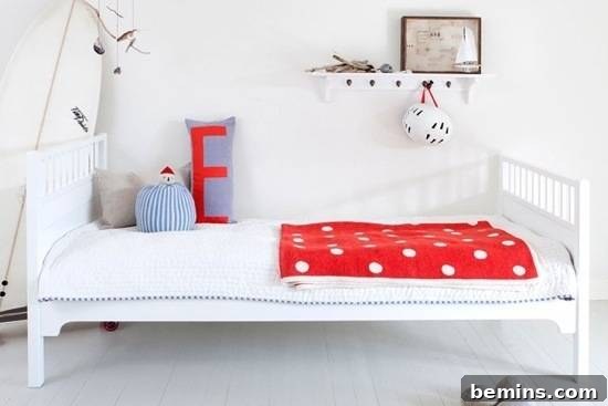 A contemporary children's bed with striking red accents, adding a vibrant touch to a minimalist bedroom design.