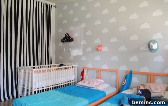 A serene room featuring a white crib and two beds with calming blue sheets, complemented by elegant black and white curtains, creating a peaceful environment.