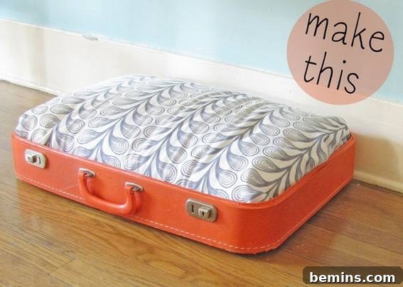 An orange suitcase with white and grey designs repurposed into a stylish dog bed, showcasing vintage charm.