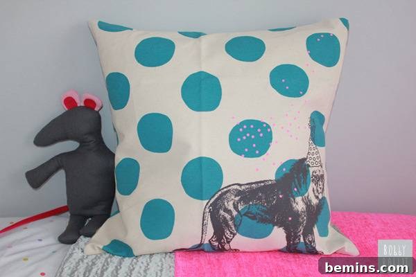 A child's bedroom has a square pillow that is white with blue dots and an animal.