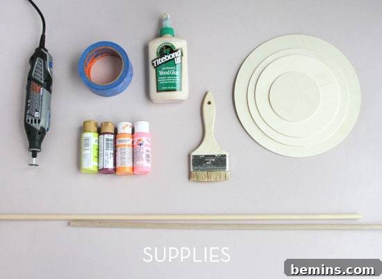 Assortment of craft supplies, including paint bottles, paintbrushes, blue painter's tape, and pre-cut circular wooden pieces.
