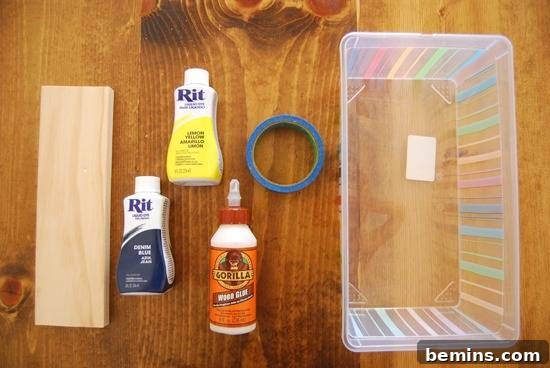 Piece of wood with bottles of dye and painter's tape near a plastic bin.